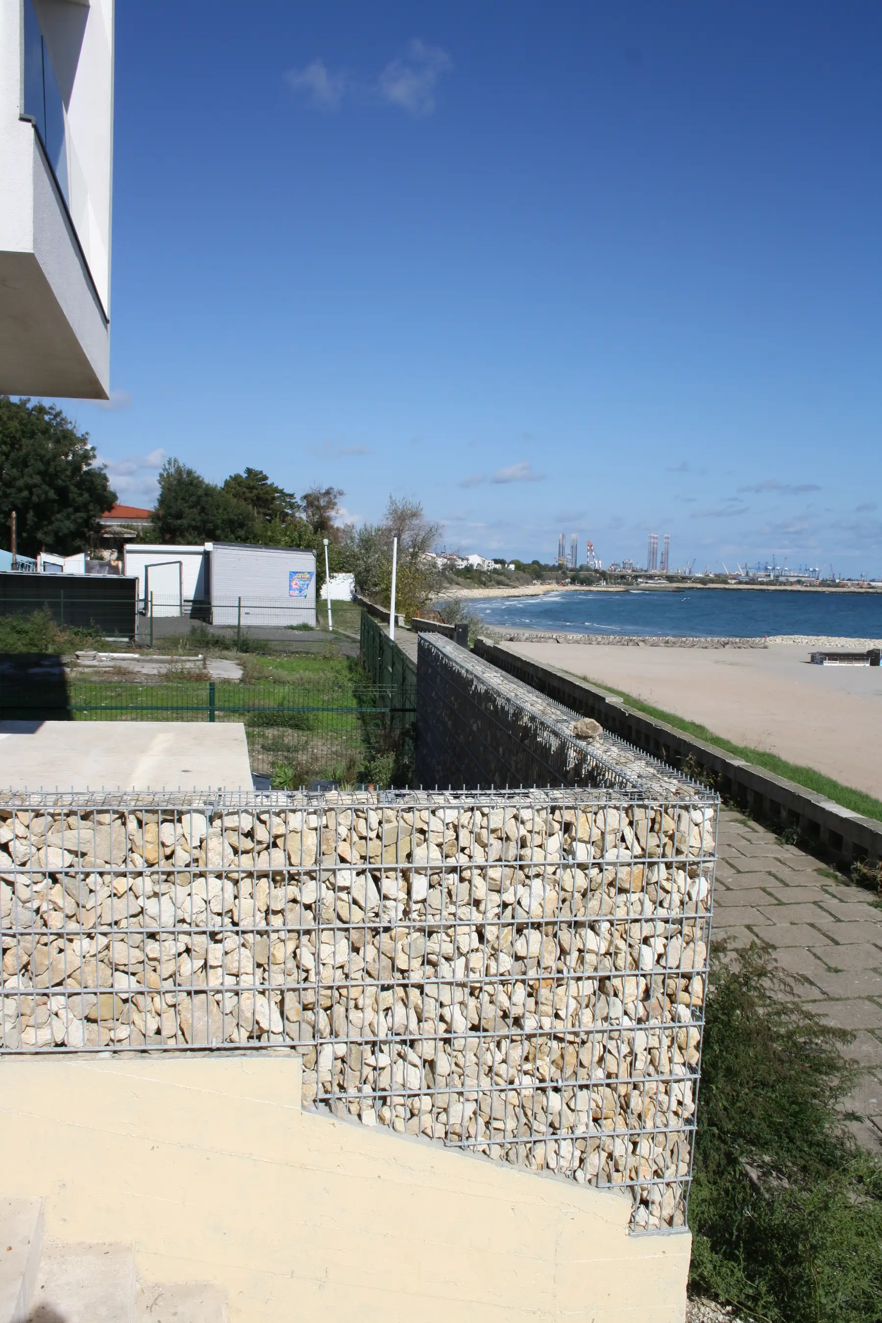 Gard din gabioane cu piatră – proprietate delimitată, plajă în fundal