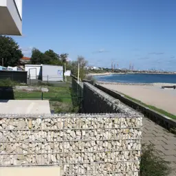 Gard din gabioane cu piatră – proprietate delimitată, plajă în fundal