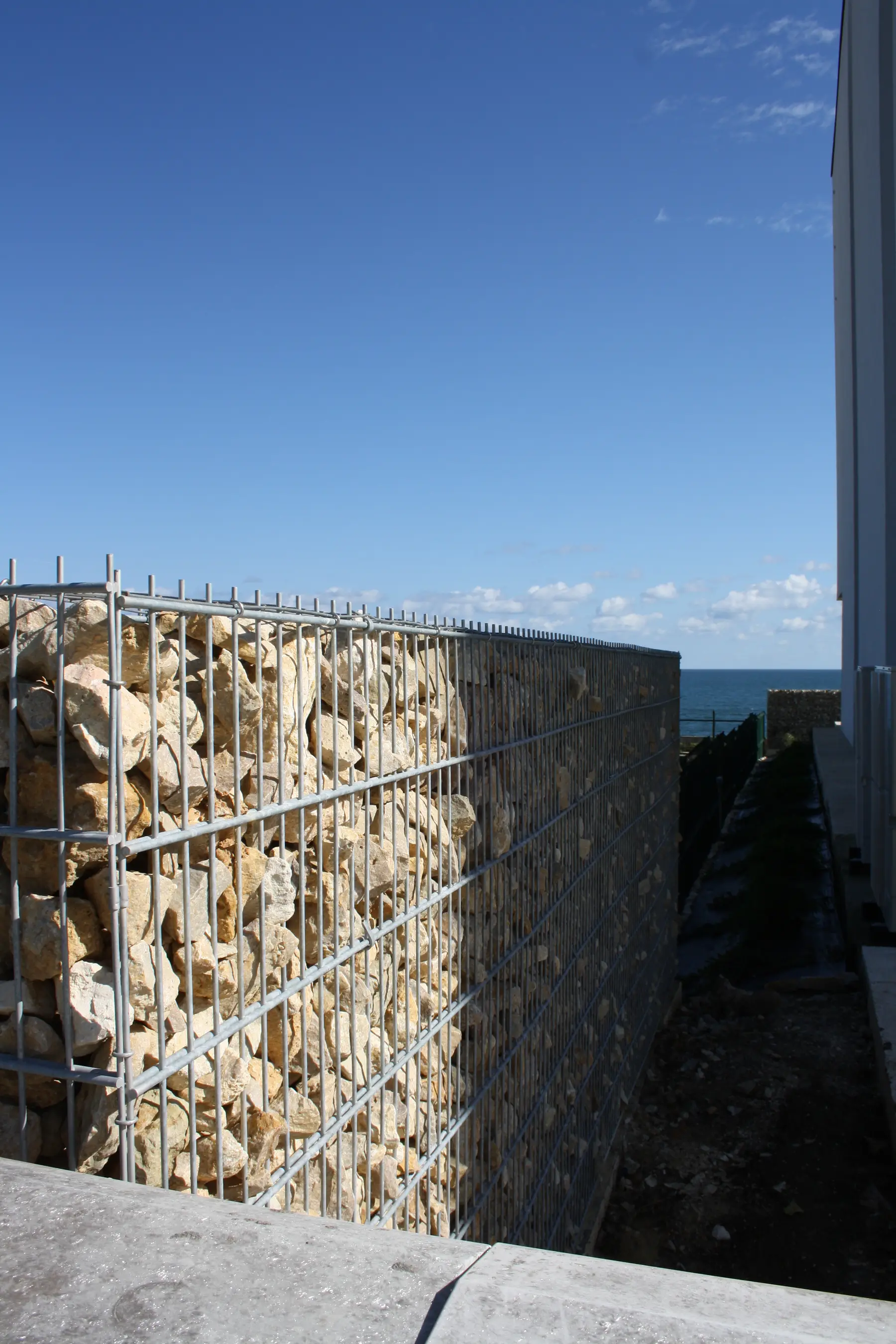 Gard din gabioane cu piatră – peisaj natural, cer albastru