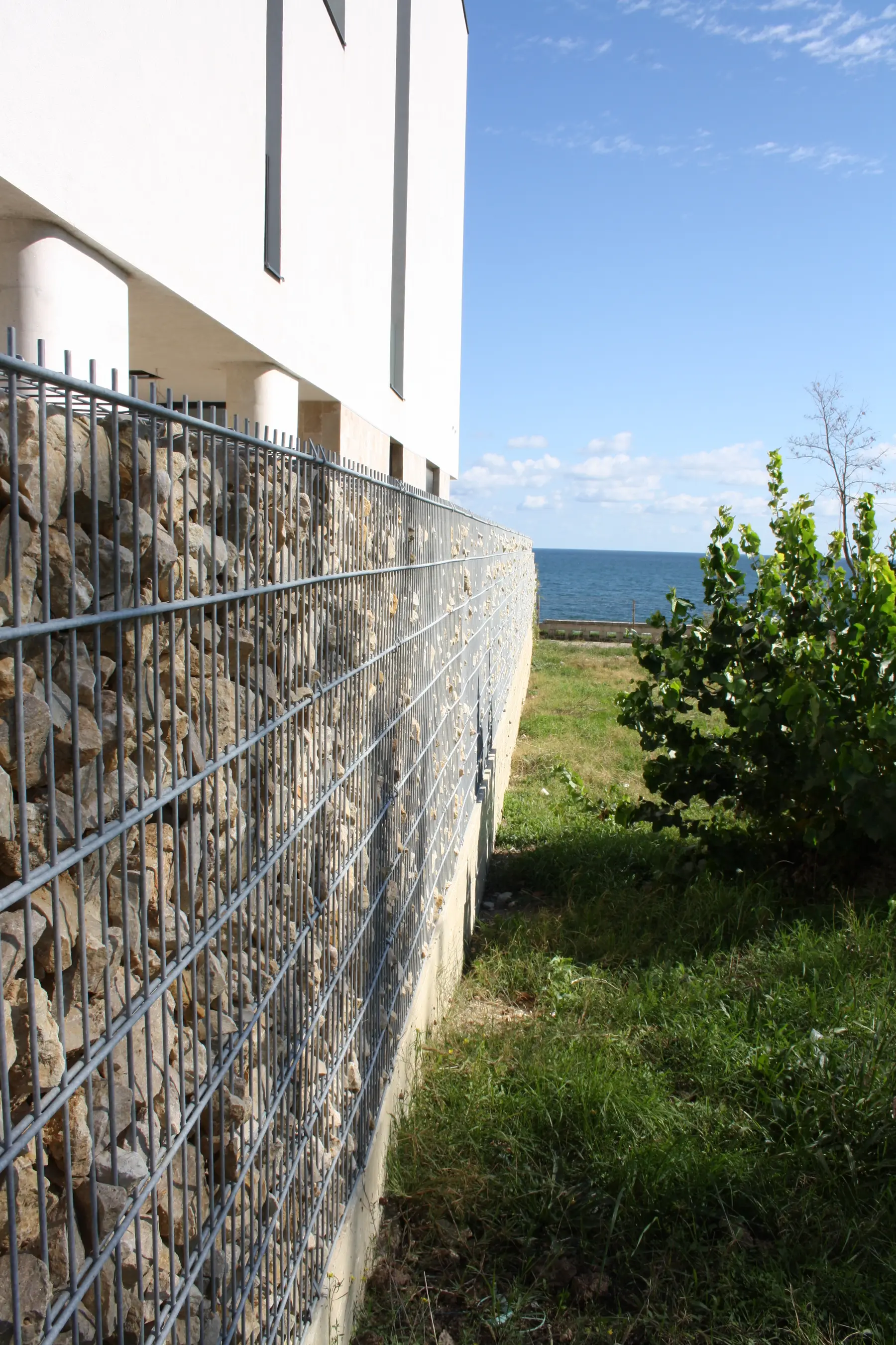 Gard din gabioane cu piatră – lângă zonă verde, vedere spre apă