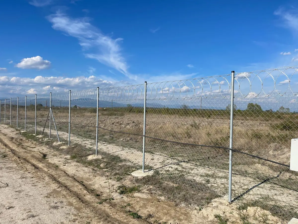 Gard de securitate cu plasă împletită zincată Flexyfort, parc fotovoltaic LPV – spirale de sârmă ghimpată, drum de pământ