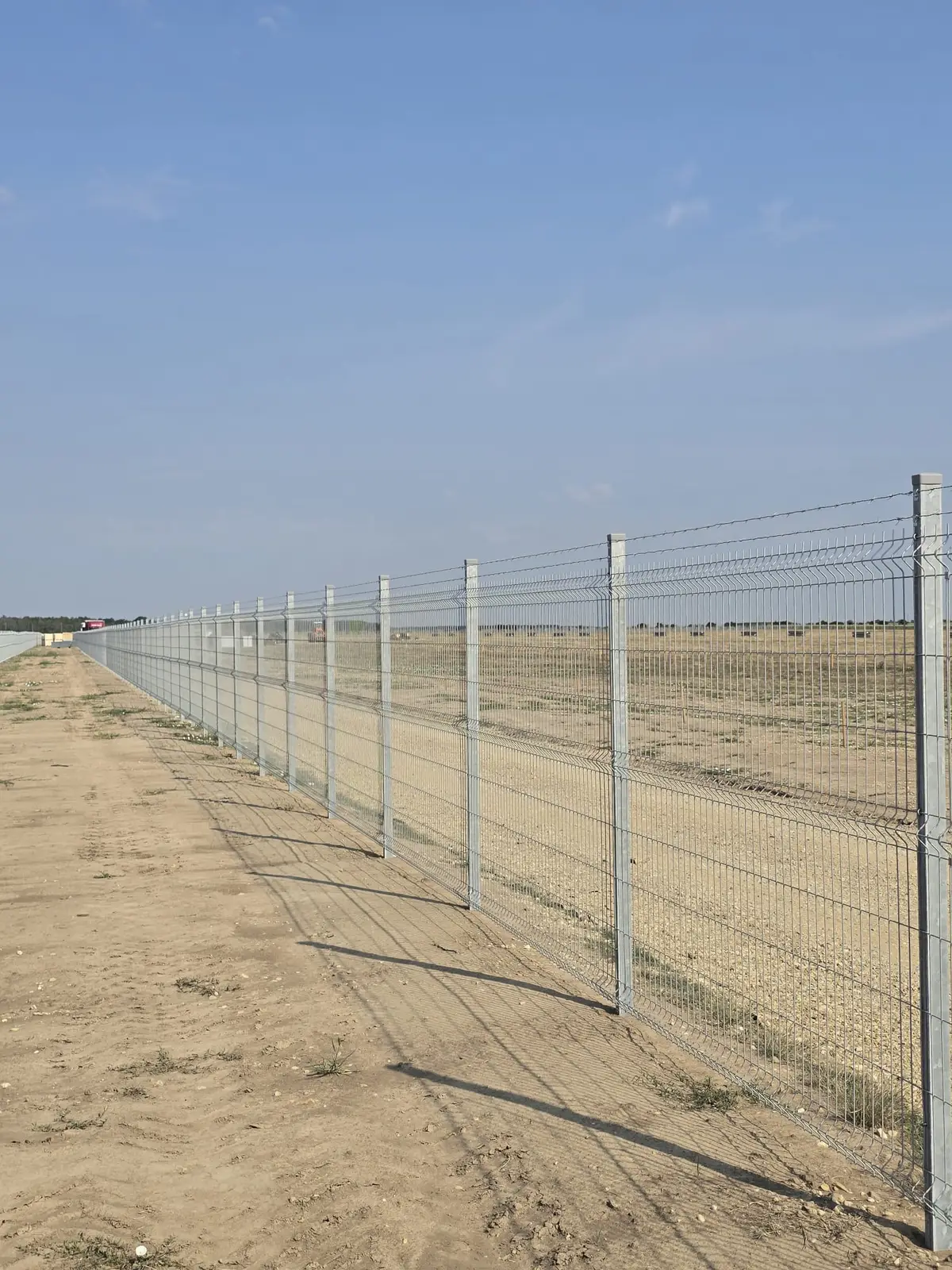 Împrejmuire parc fotovoltaic Răscăeți cu panouri bordurate zincate la cald – câmp deschis în fundal