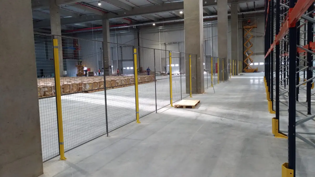 Partiționare interioară cu panouri din plasă în depozitul eMag – plasă pe stâlpi galbeni lângă mărfuri