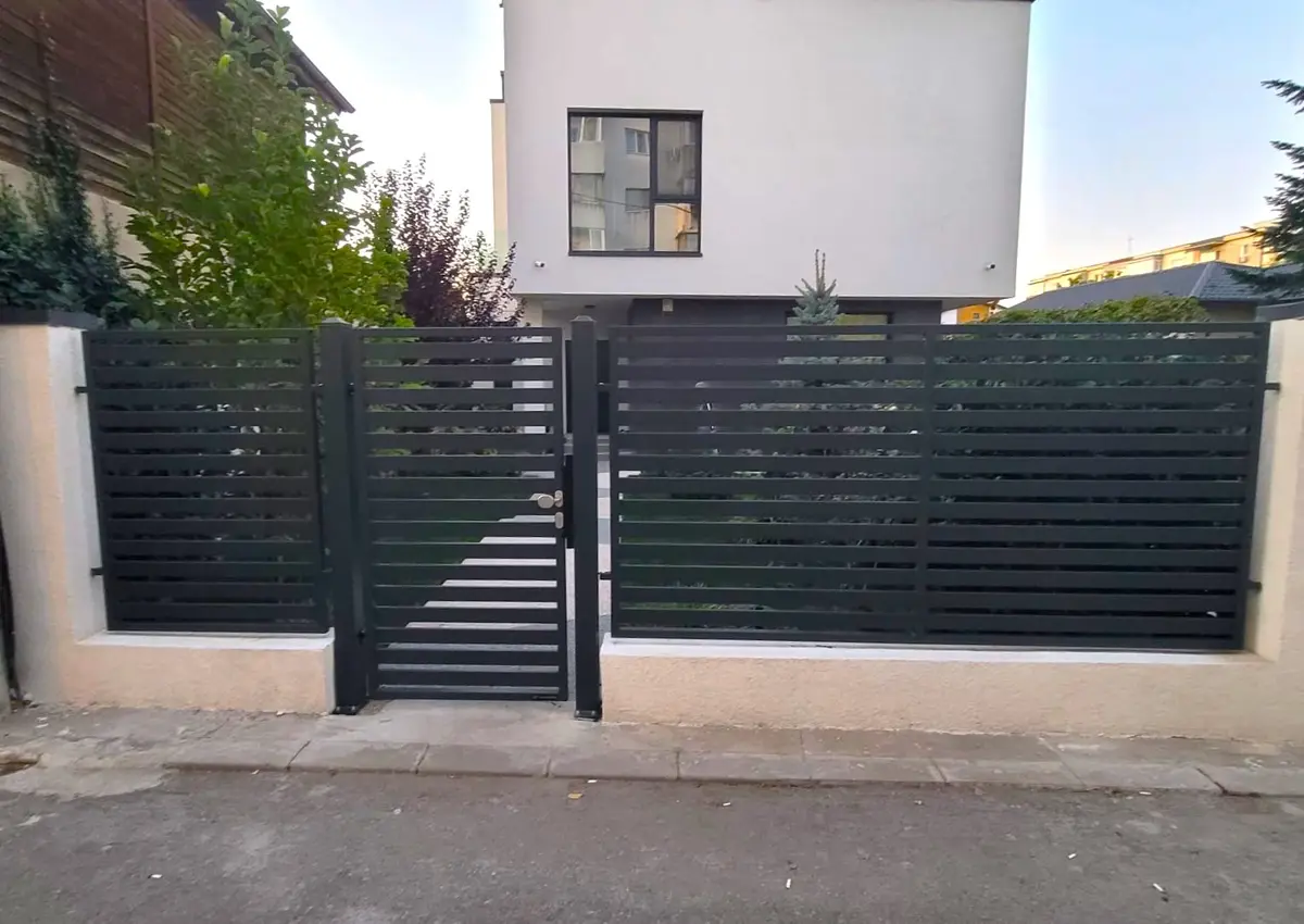 Poartă bifold cu deschidere în W și gard 10.104 la o locuință – poartă și gard de culoare închisă