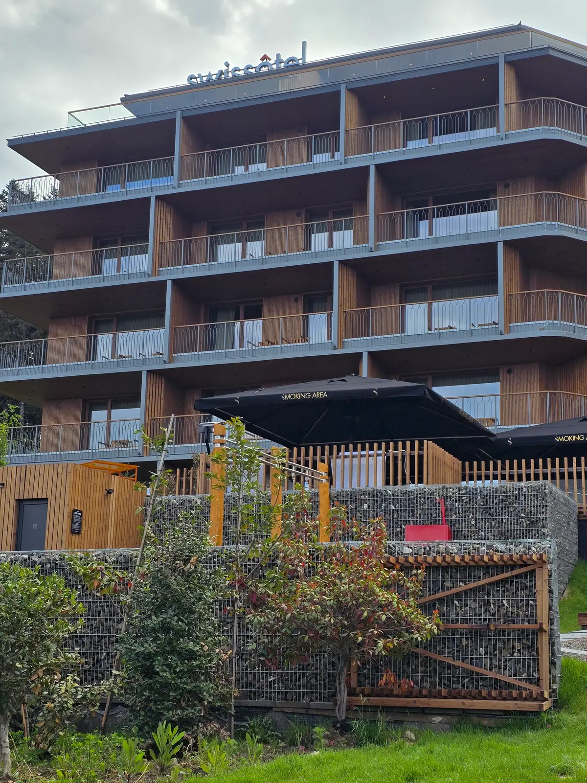 Gard din gabioane la hotelul Swissotel, Poiana Brașov – gabion cu panou de lemn în fața clădirii